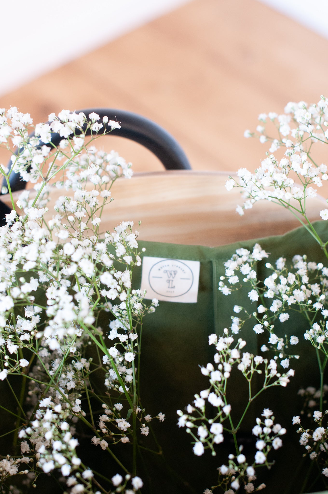 Interior of a green shopping bag with a woven library label sewn in and filled with flowers