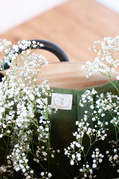 Interior of a green shopping bag with a woven library label sewn in and filled with flowers