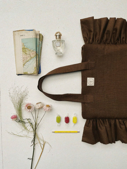 Flat lay with Irish linen brown ruffle bag, sweets, a map, perfume and dried flowers
