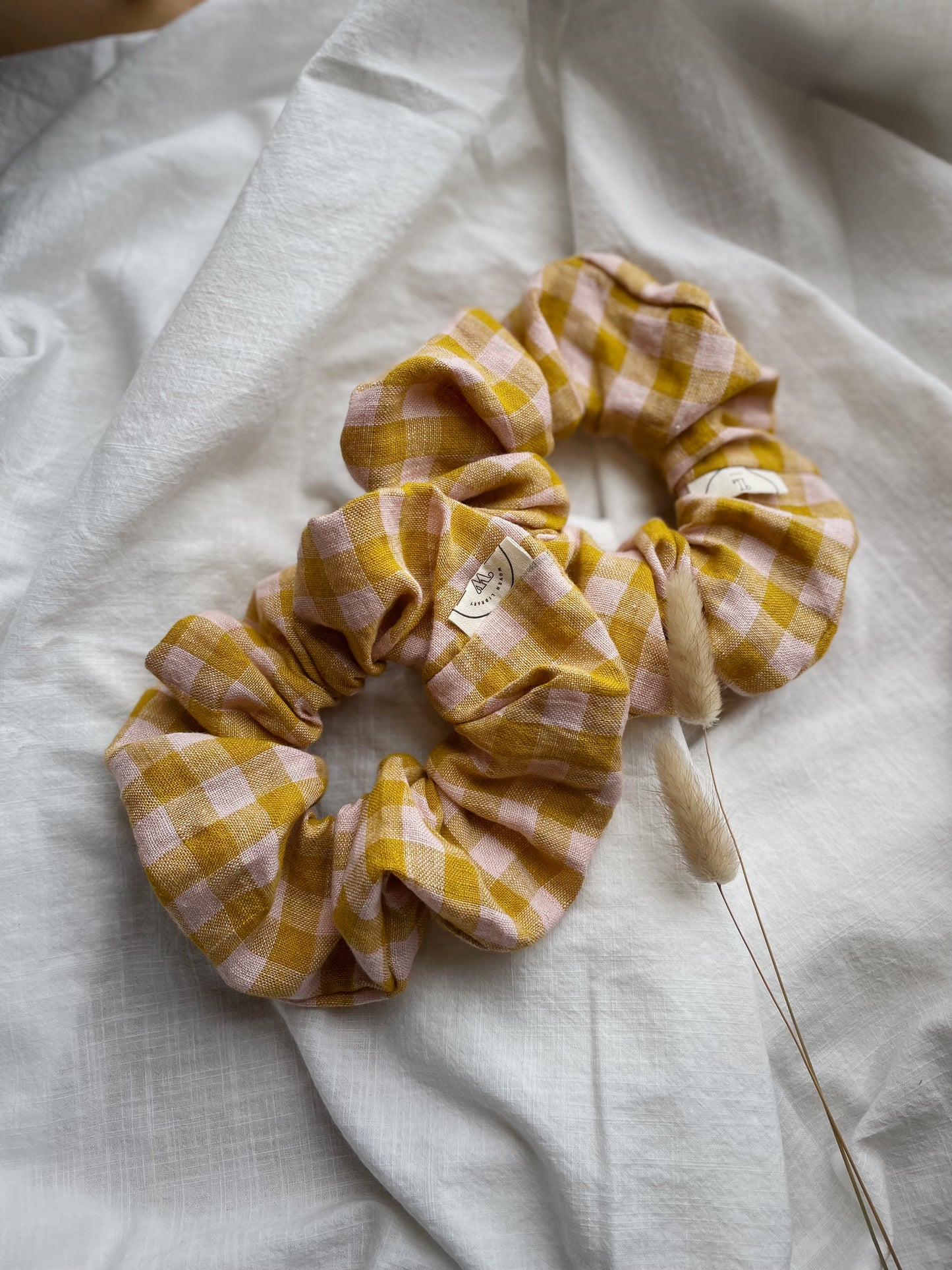 Oversized checked scrunchies places on a white piece of fabric