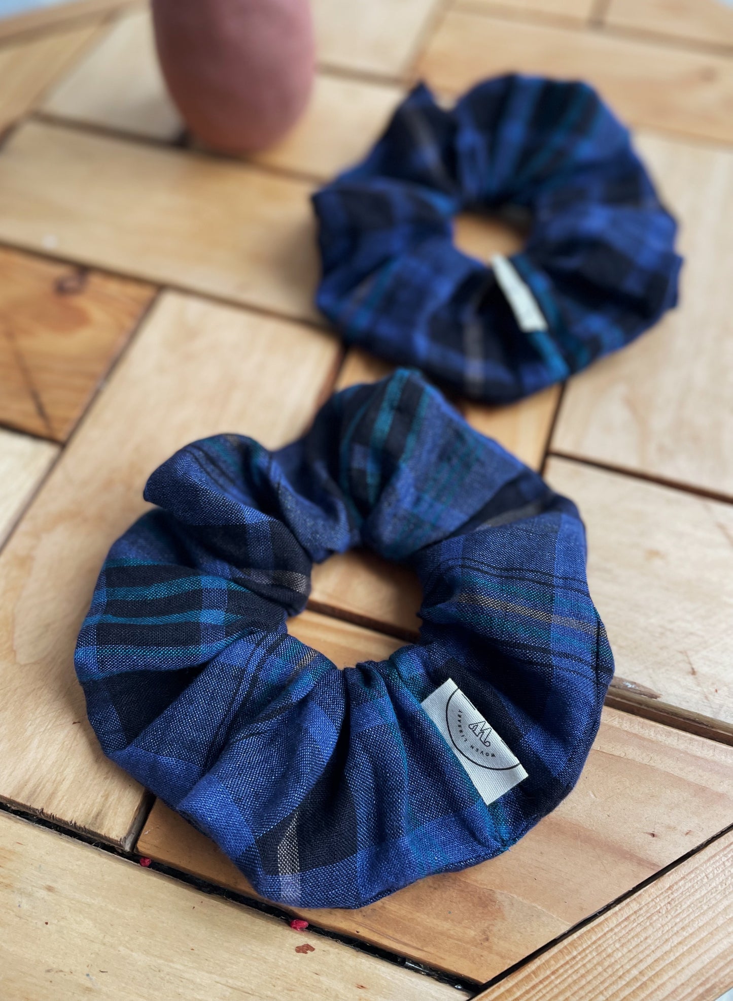 Two blue plaid scrunchies on a wooden surface
