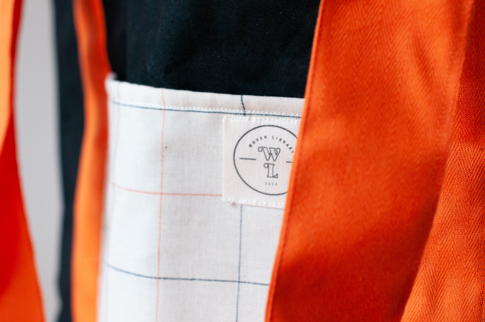 A black and orange tote bag with two large exterior pockets and multiple interior pockets, adorned with a floral arrangement.