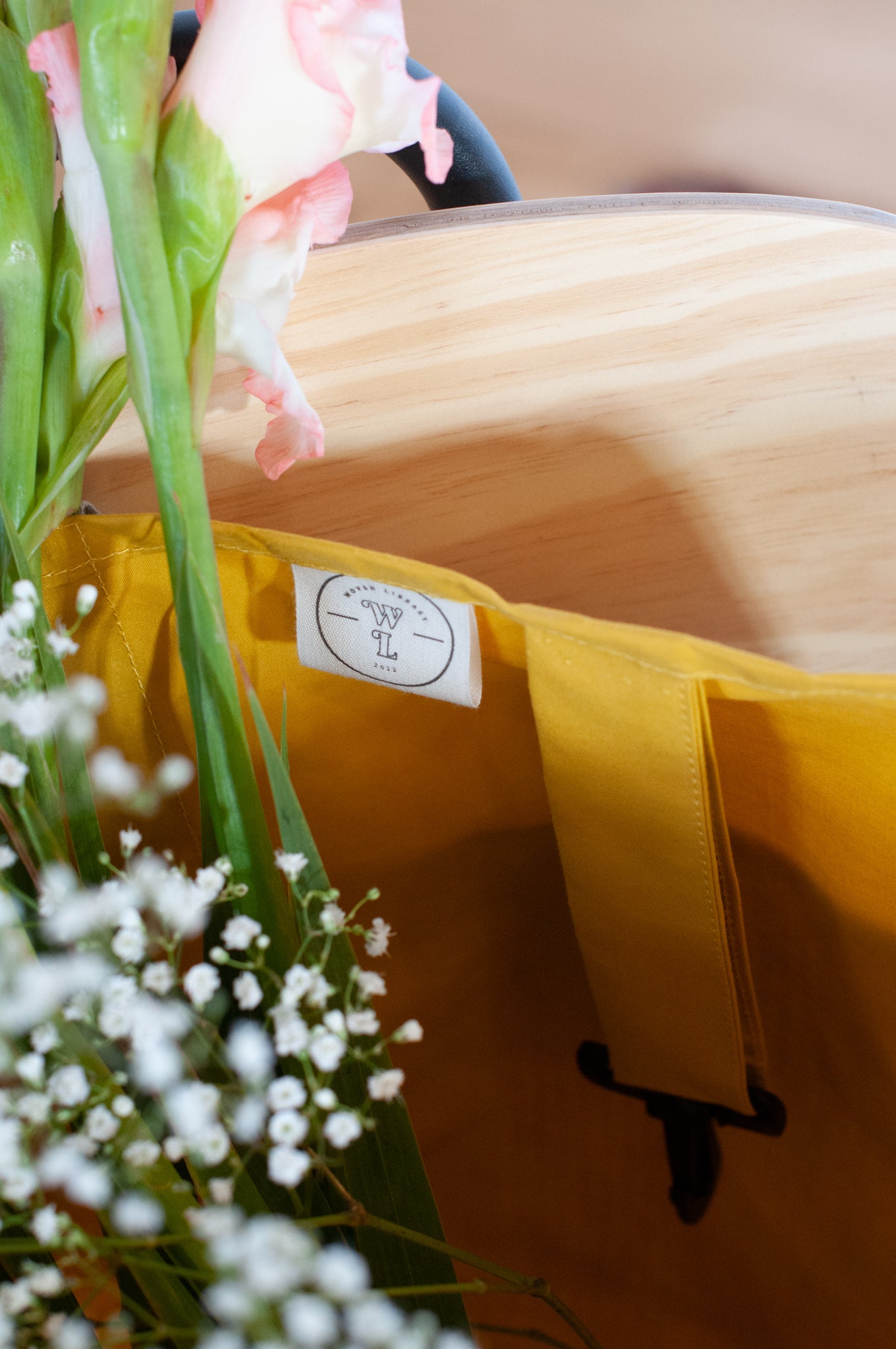This image shows the inside of a yellow shopping bag with a label for woven library and a hanging clip for you to place your keys